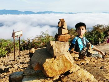 Portrait of boy holding rocks while sitting on land