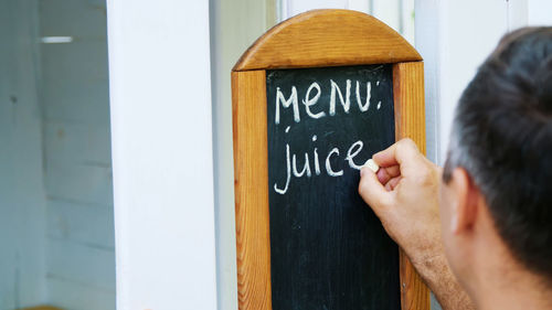 Close-up, on blackboard man writing with white chalk, words-menu, juice