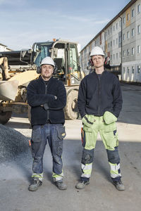 Full length portrait of confident workers standing at construction site