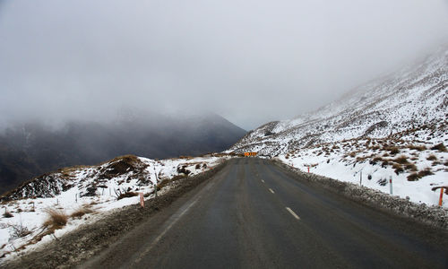 Road amidst snowcapped mountains against sky