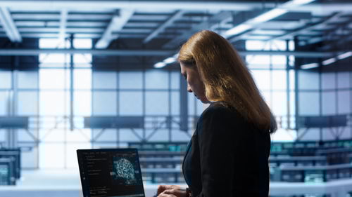 Rear view of woman using laptop at airport