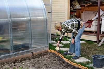 Full length of woman watering plant at botanical garden