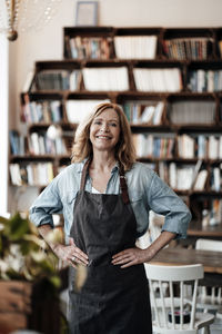 Happy female cafe owner standing with hand on hip