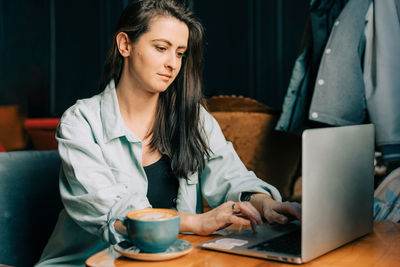 Young woman using mobile phone while sitting on table