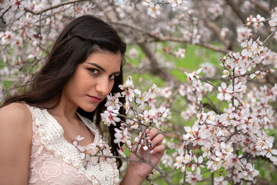 Portrait of young woman with cherry blossoms in spring