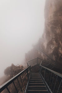 Staircase leading towards mountain against sky