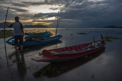 Boats moored on beach against sky during sunset