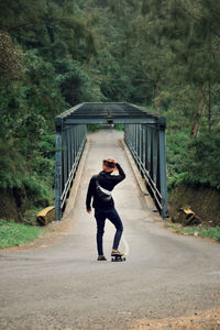 Full length of man with skateboard on road 