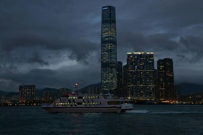 Ferry boat in victoria harbour against illuminated skyscrapers at dusk