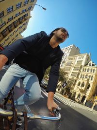 Low angle view of man sitting against buildings in city