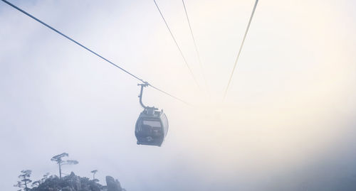 Low angle view of overhead cable car against sky