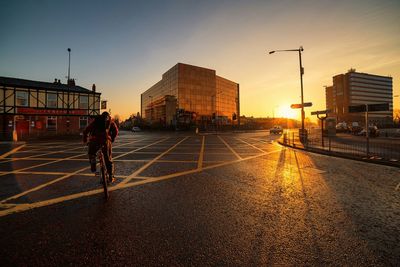 People walking on road in city at sunset