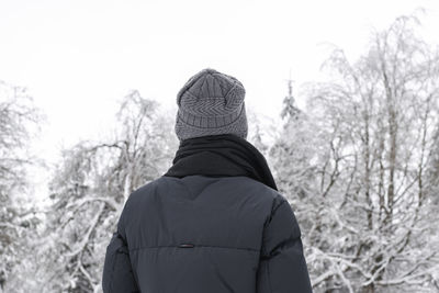 Portrait of a young man from the back in the winter forest.