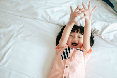 Midsection of child lying on bed at home