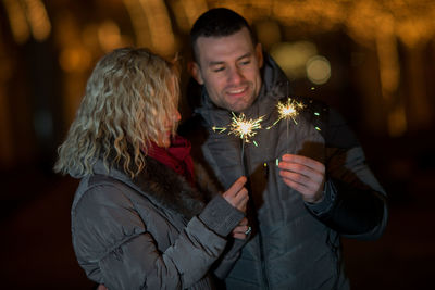 Couple with burning sparklers at night during christmas