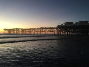 Bridge over sea against sky during sunset