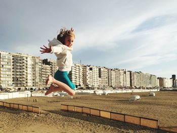 Full length of boy jumping in city against sky