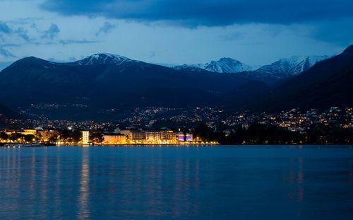 View of river and illuminated city against mountains