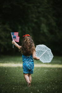 Rear view of woman with umbrella on field