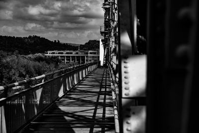Footbridge against cloudy sky