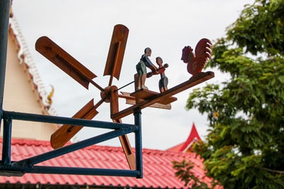 Low angle view of men working on wood against sky