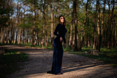 Full length portrait of woman standing in forest