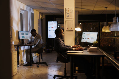 Rear view of man using laptop at office