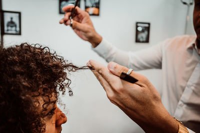 Midsection of barber cutting woman hair in salon