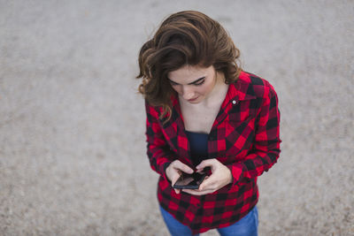 Young woman using mobile phone while standing on road