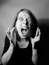 Portrait of young woman gesturing against wall