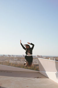 Woman jumping against clear sky