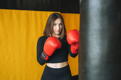 Young brunette woman in black wear engaged boxing training in fitness club gym