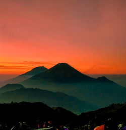 Scenic view of silhouette mountains against orange sky