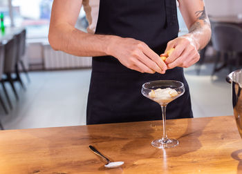 Midsection of man holding wineglass on table