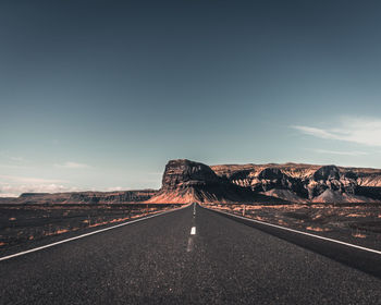 Road leading towards mountain against sky