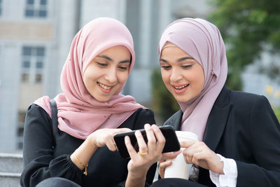 Smiling young woman using mobile phone in city