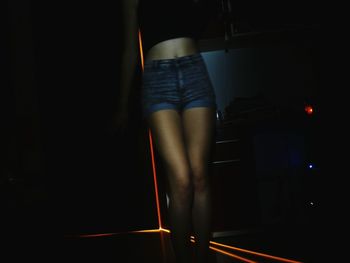Rear view of woman standing in illuminated room