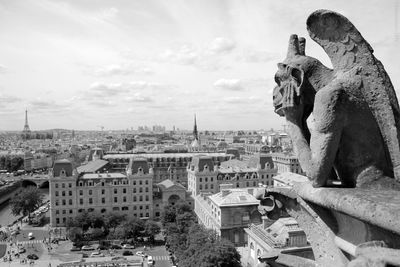 Statue in city against cloudy sky