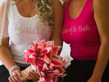 Midsection of woman holding pink flowers