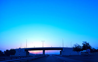 Bridge over road against clear blue sky at dusk