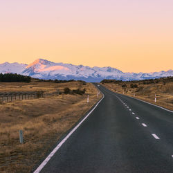 Road by landscape against clear sky during sunset