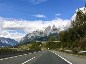 Road by mountains against sky