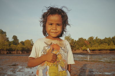 Portrait of cute smiling boy standing against sky