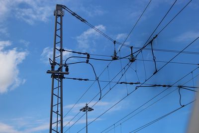 Low angle view of electricity pylon against blue sky