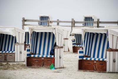 Hooded chairs on beach against clear sky