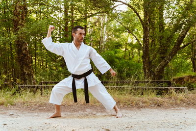 Man with karategi practicing martial arts in the forest