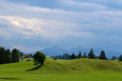 Scenic view of grassy field against cloudy sky
