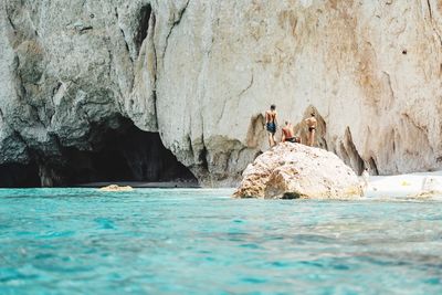 People on rock by sea