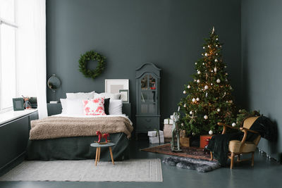 Decorated christmas tree to basket stands in dark vintage bedroom