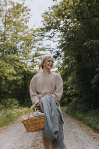 Smiling woman holding wicker basket and looking away